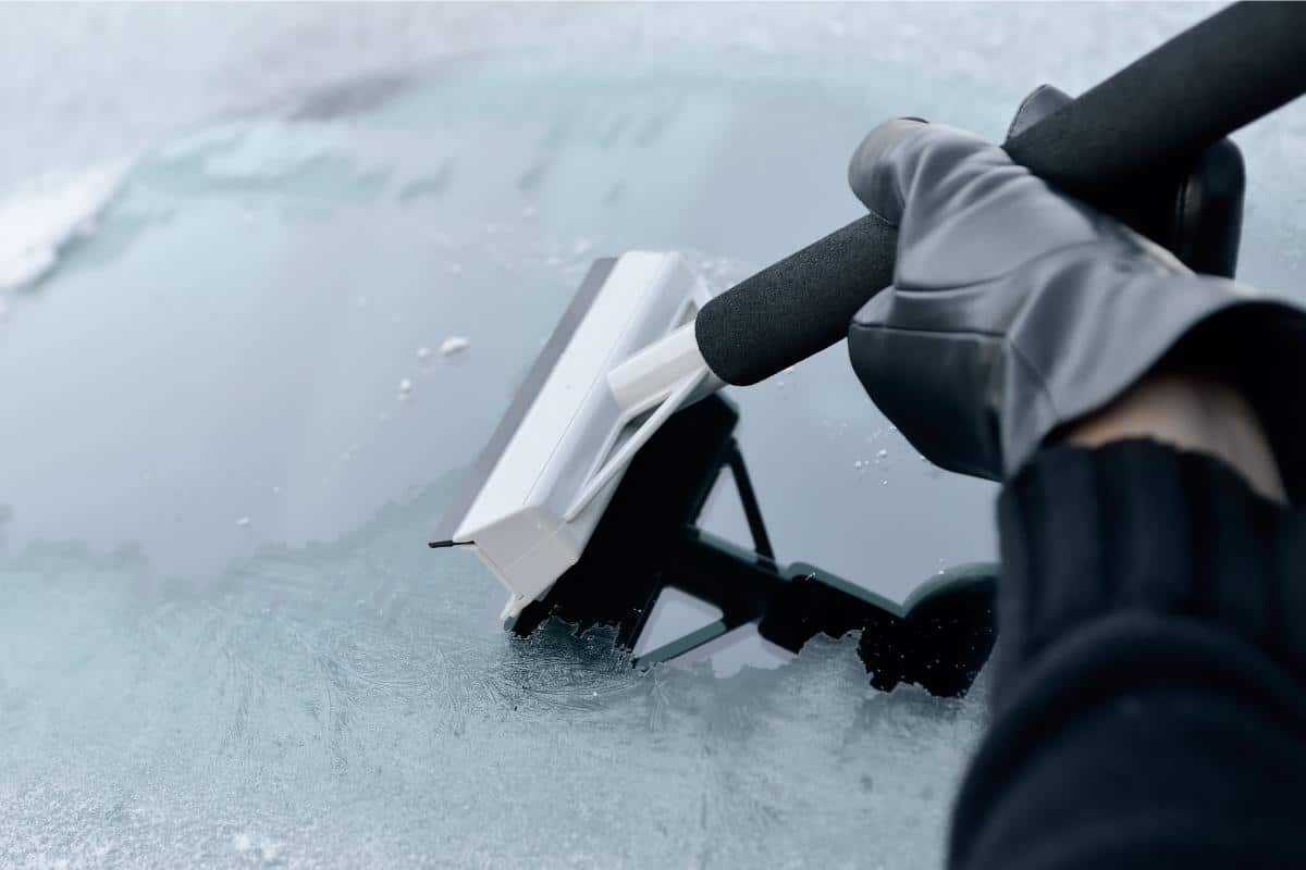 En man rengör vindrutan på en bil med en speciell borste.