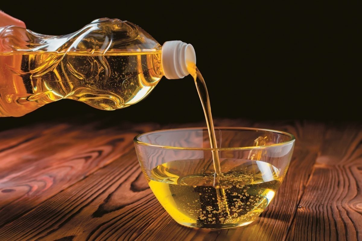 häller vegetabilisk olja i en kopp